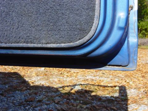 1985 Ford F-250 - Detail shot of the lower door frame and interior carpet of a vehicle, with the ground visible outside.