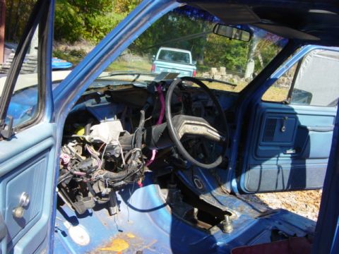 1985 Ford F-250 - The interior of a blue pickup truck is shown with its dashboard disassembled, revealing wiring and exposed wiring.
