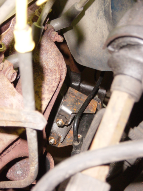 1985 Ford F-250 - Close-up of engine components, including a mount and exhaust manifold, with visible rust and wiring.