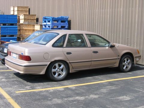 1991 Ford Taurus - Side view of a 1991 Ford Taurus sedan parked in a lot next to another vehicle.