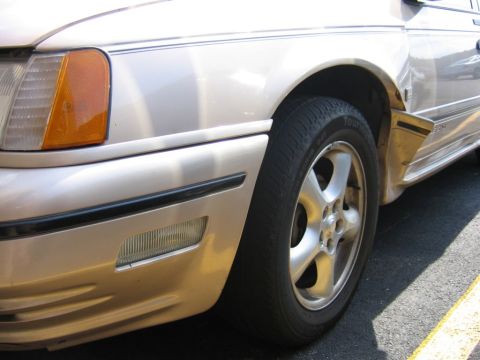 1991 Ford Taurus - Close-up of the front fender and wheel of a 1991 Ford Taurus.