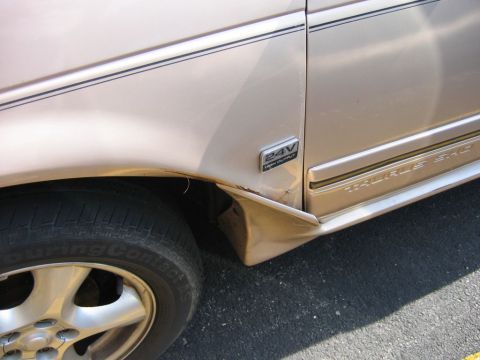 1991 Ford Taurus - Detail shot of a car's side panel, showing the wheel well and a '24V HIGH OUTPUT' badge.