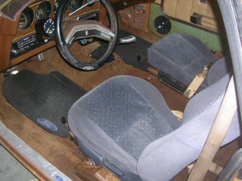 1975 Ford Ranchero - The interior of a vehicle shows bucket seats, a steering wheel, and floor mats. The year is not discernible from the image.