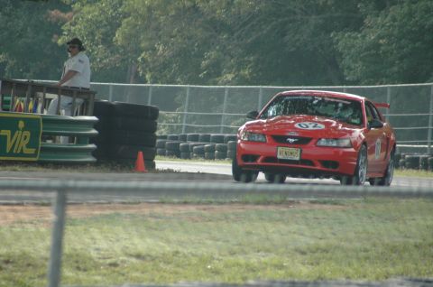 2000 Ford Mustang - A red 2000 Ford Mustang with racing decals and the number 02 visible drives on a race track.