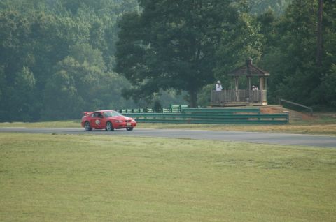 2000 Ford Mustang - Red 2000 Ford Mustang on a race track, with a gazebo and trees visible.