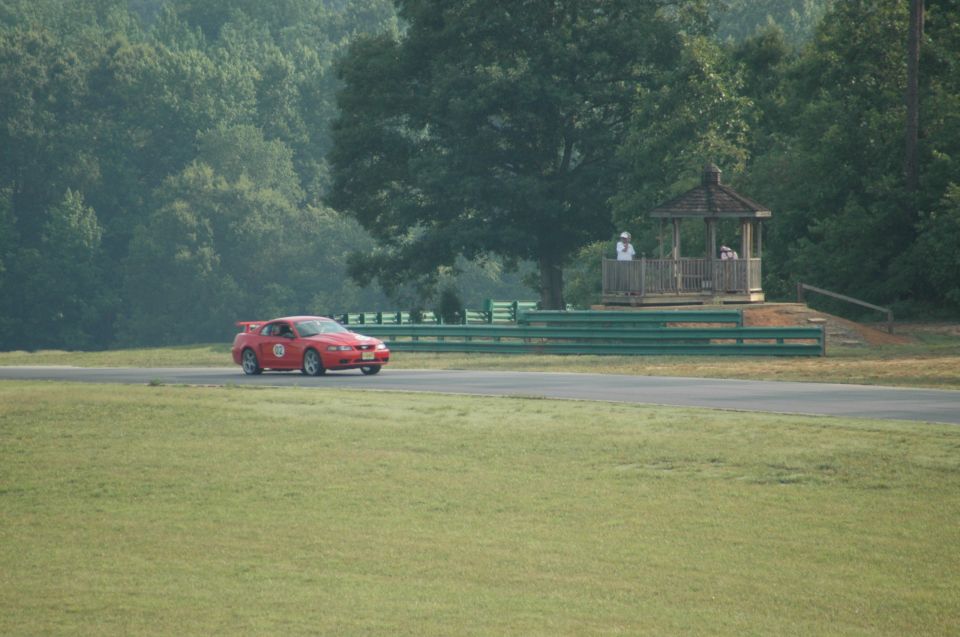 Red 2000 Ford Mustang on a race track with a gazebo in the background