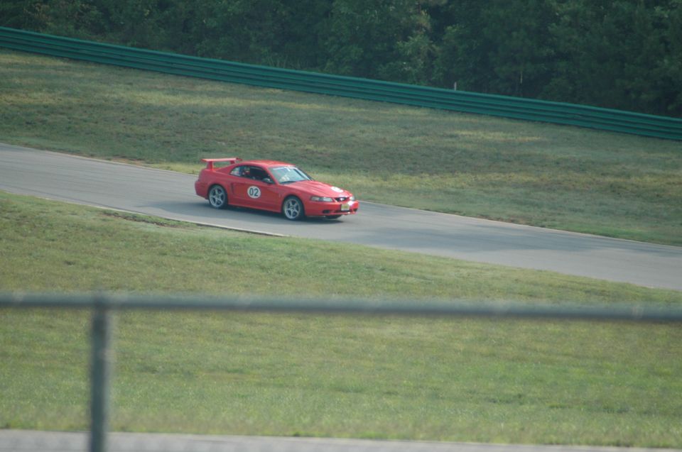 Red 2000 Ford Mustang with racing decals and a spoiler on a racetrack