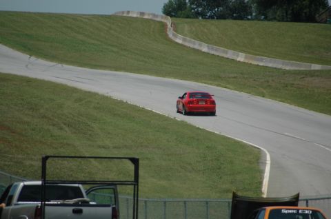 2000 Ford Mustang - A red 2000 Ford Mustang navigates a turn on a race track.