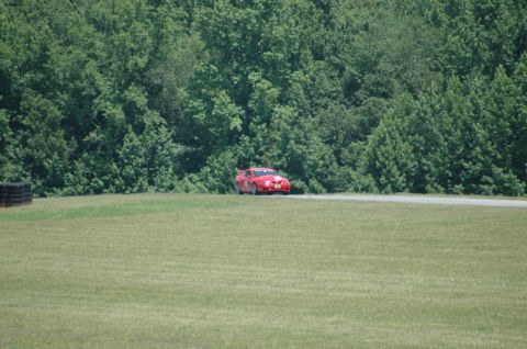 2000 Ford Mustang - A red 2000 Ford Mustang is seen on a race track with a wooded area in the background.