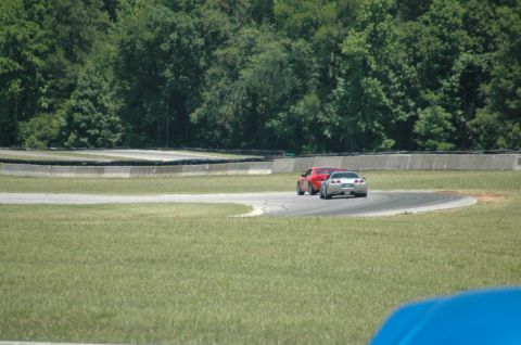 2000 Ford Mustang - Two sports cars, a silver one and a red one, navigate a curve on a race track.