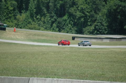 2000 Ford Mustang - A red car is seen on a race track with another car in the distance.