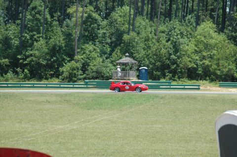 2000 Ford Mustang - A red 2000 Ford Mustang is seen on a race track with trees and a gazebo in the background.