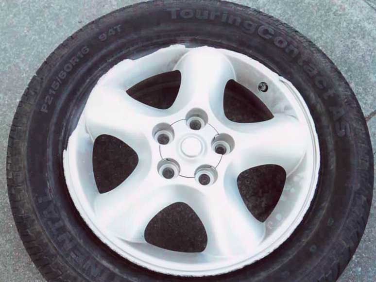 Silver 5-spoke 16-inch alloy wheel with Continental TouringContact AS P215/60R16 tire on pavement
