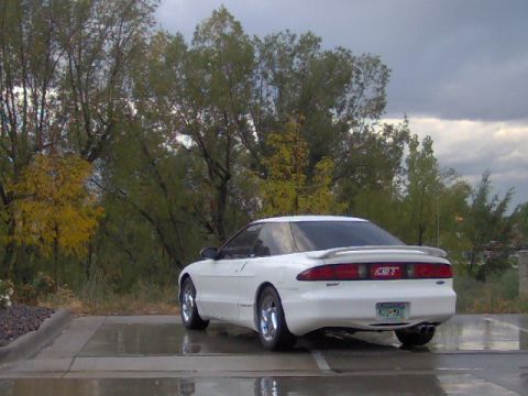 1996 Ford Probe - A white Ford Probe is parked on a wet surface with trees in the background.