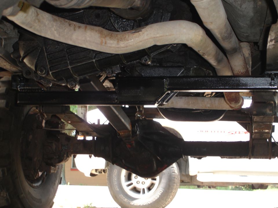 Underside view of a vehicle's drivetrain, showing the transmission, exhaust pipes, and rear axle assembly