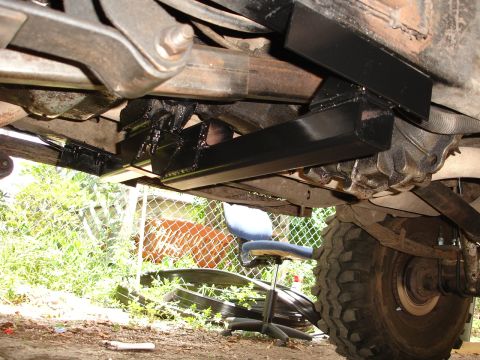 1989 Ford Bronco - Close-up view of the undercarriage, focusing on a newly installed crossmember and a large off-road tire.