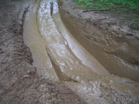 1989 Ford Bronco - Deep tire tracks carved into the mud indicate a vehicle has recently passed through this challenging terrain.