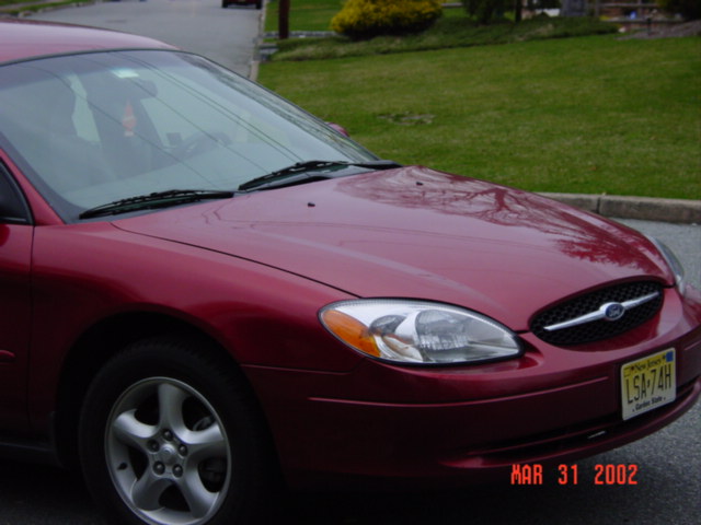 Front three-quarter view of a dark red Ford Taurus sedan with New Jersey plate LSA-74H