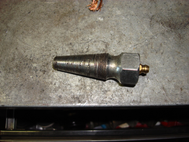 Tapered threaded automotive fitting with a grease zerk on a workbench