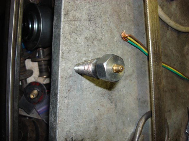 Tapered threaded metal fitting standing upright on a metal tray