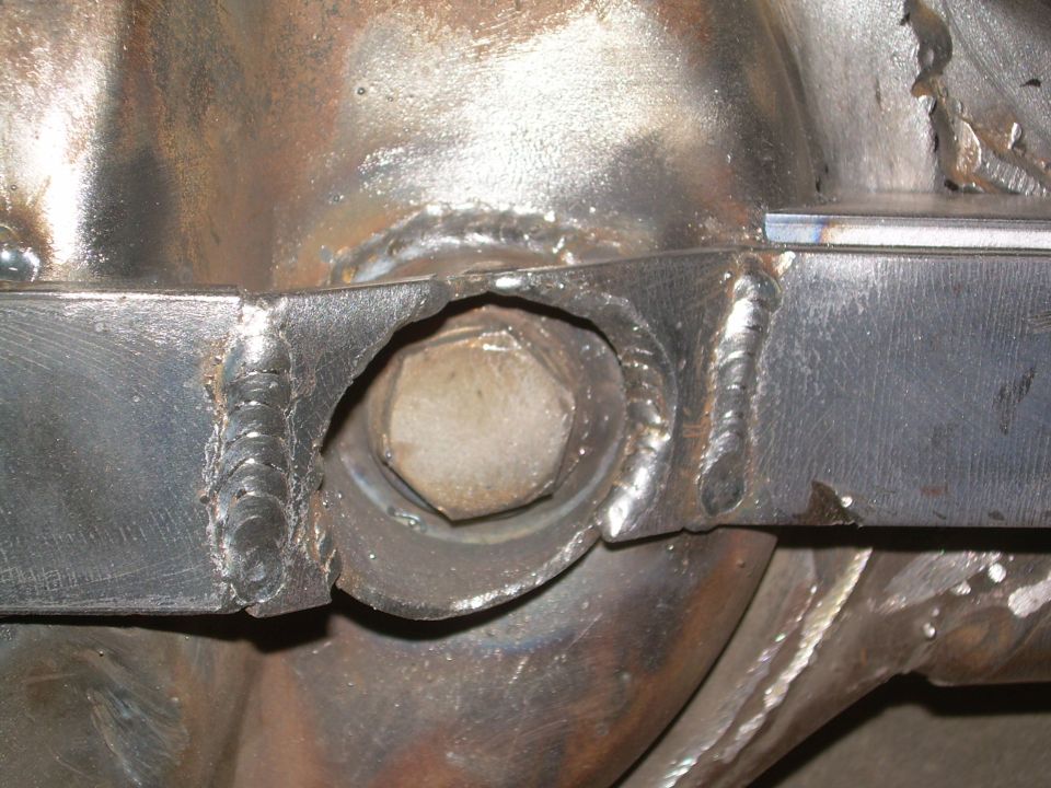 Close-up of a welded metal bracket with a large bolt head visible through a hole