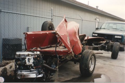 1967 Ford F-100 - Chassis of a wrecked red pickup truck with its engine and transmission exposed, parked next to another vehicle.