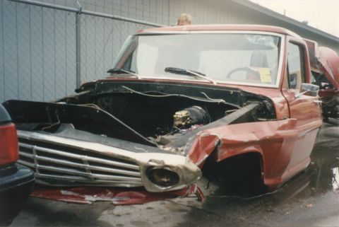 1967 Ford F-100 - This damaged red pickup truck is missing its engine and has significant front-end damage.