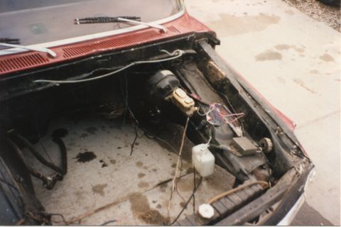 1967 Ford F-100 - The engine bay of a 1967 Ford F-100 shows the brake booster and master cylinder, with wiring and hoses exposed.