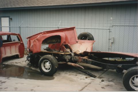 1967 Ford F-100 - Two heavily damaged red pickup trucks sit in a yard, one appearing to be a chassis and the other a cab.