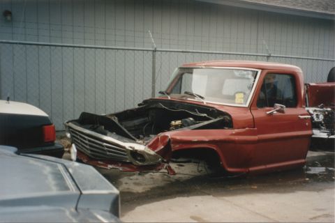 1967 Ford F-100 - Front view of a damaged 1967 Ford F-100 truck cab in a wrecking yard.