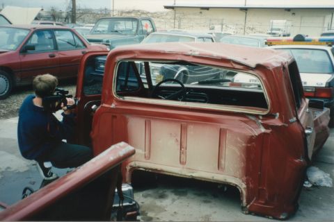 1967 Ford F-100 - Rear view of a damaged 1967 Ford F-100 pickup truck in a junkyard setting.