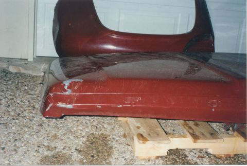 1967 Ford F-100 - Two red truck body parts, likely a bed and fender, are stored on wooden pallets.