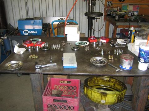 1987 Suzuki Samurai - A workbench is cluttered with various automotive parts and tools, suggesting a repair or assembly process is underway.