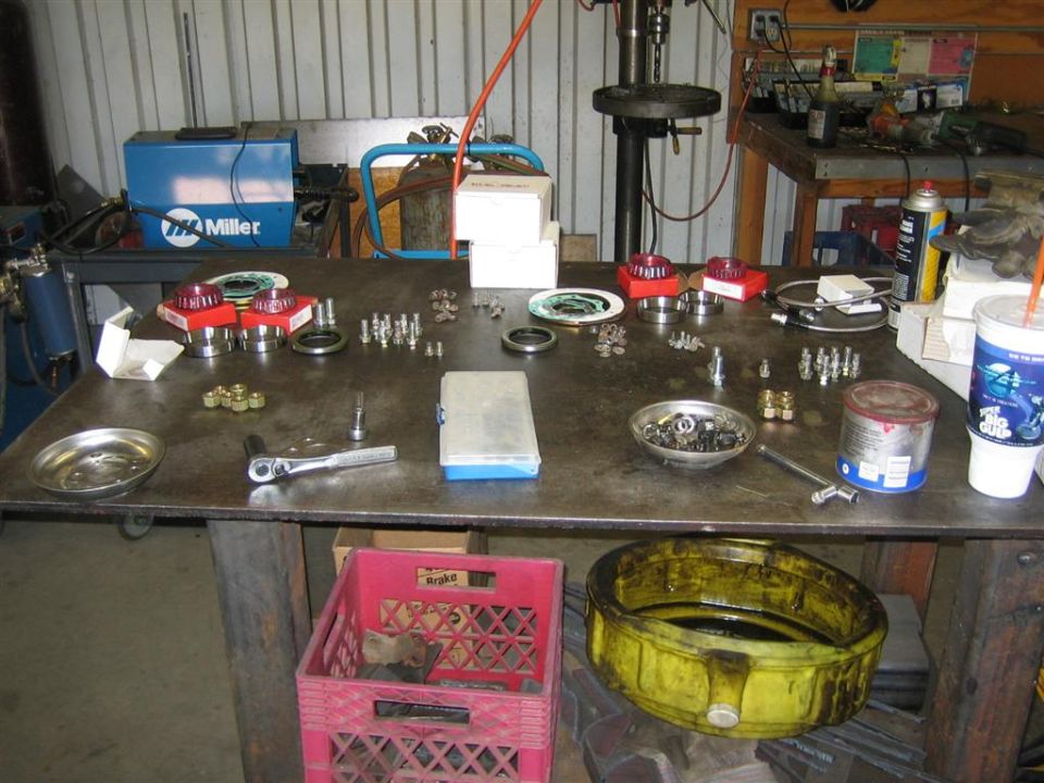 Workbench with assorted automotive parts and tools, including bearings and bolts