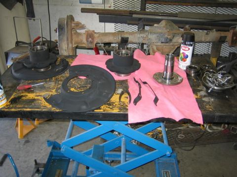 1987 Suzuki Samurai - Various front axle parts are disassembled and organized on a workbench for maintenance or repair.