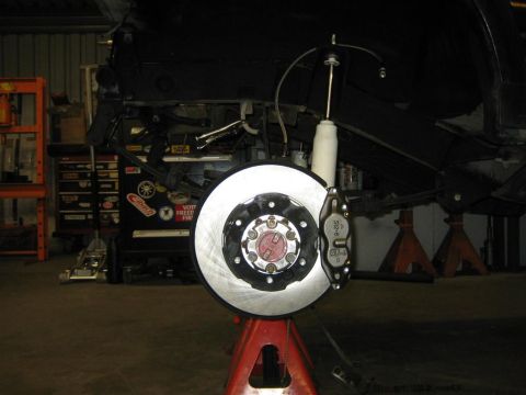 1987 Suzuki Samurai - Close-up of a vehicle's front axle assembly, including a brake rotor and caliper, supported by a jack stand.