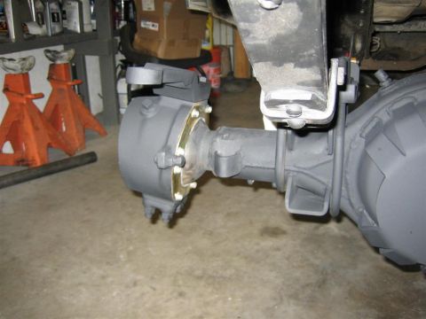 1987 Suzuki Samurai - The front axle assembly of a vehicle is shown, with suspension parts attached, in a garage setting.