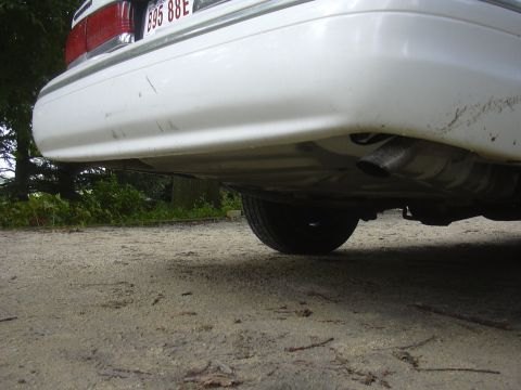 1997 Ford Crown Victoria - Rear view of a white 1997 Ford Crown Victoria, showing the bumper, exhaust, and a portion of the tire.