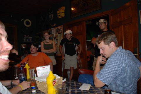1996 Ford Bronco - A group of friends are socializing at tables in a bar, with one person using crutches.