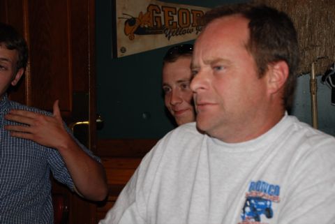 1996 Ford Bronco - A group of men are gathered indoors, with one man's sweatshirt a graphic that includes the word "Bronco".