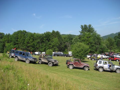 1991 Ford Bronco - Multiple off-road vehicles gathered on a sunny day in a rural, wooded area.