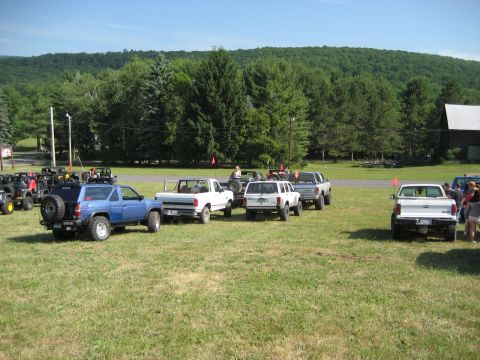 1991 Ford Bronco - A collection of off-road vehicles are gathered in an open, grassy area on a sunny day.
