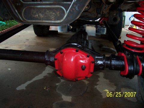 1988 Ford Bronco - Close-up view of a vehicle's rear axle differential with a red cover and a red coil spring visible.