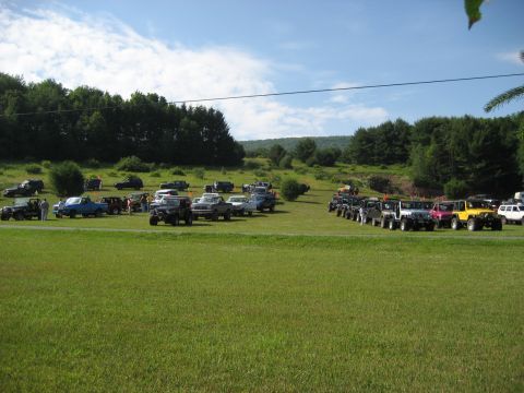 1991 Ford Bronco - A large gathering of off-road vehicles are parked in a grassy field on a sunny day.