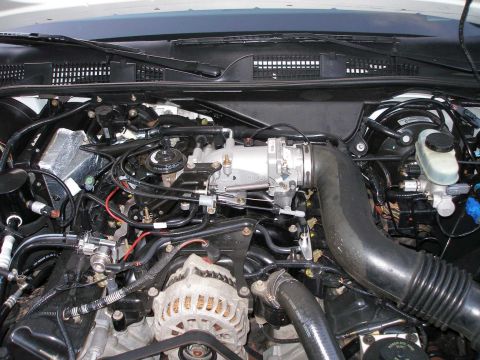 2001 Ford Crown Victoria - Close-up view of a vehicle's engine bay, focusing on the throttle body assembly and surrounding components.