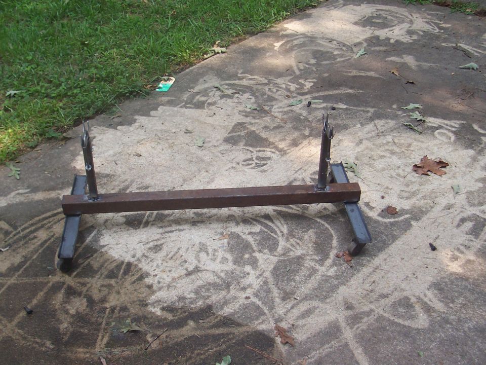 Metal axle stand with two upright prongs and four angled legs on concrete