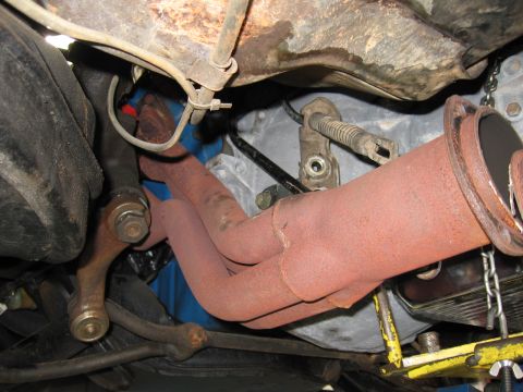 1973 Ford Ranchero - Close-up view of the exhaust manifold and transmission linkage, showing rust and mechanical components.