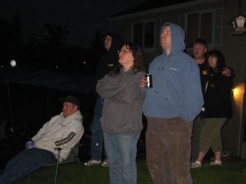 2000 Ford E350 - Several people stand and sit outdoors at night, appearing to watch an event.