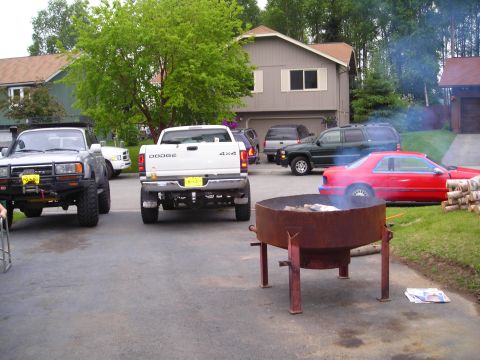 2003 Jeep TJ - A white Dodge pickup truck and a silver Toyota Land Cruiser are parked in a driveway next to a house.