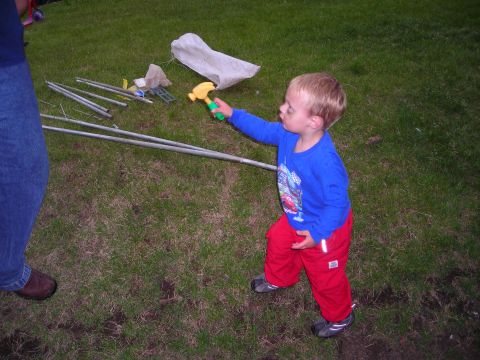 2003 Jeep TJ - Child playing with a toy hammer on grass with some metal poles nearby.